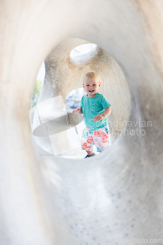 Image of Child playing on outdoor playground. Toddler plays on school or kindergarten yard. Active kid on stone sculpured slide. Healthy summer activity for children. Little boy climbing outdoors.