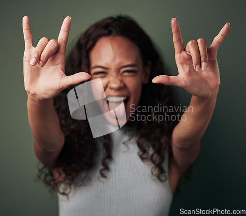 Image of Woman, portrait and rock hand in green studio background shows tongue with emoji and crazy. Female person, rocker and gesture with hands to celebrate or winning with excited face for a party.