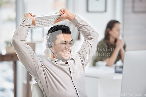 Image of Call center, smash or angry man in customer service frustrated by consulting or tired of stress. Burnout, anger or upset Asian sales agent talking or smashing a keyboard at tech support in office