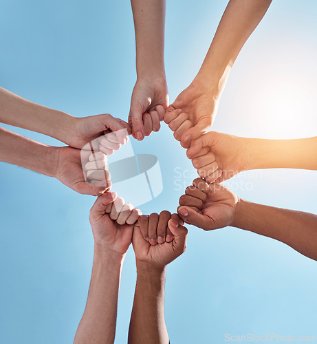 Image of Diversity, fist pump and hands in a circle together for unity, collaboration and teamwork. Solidarity, empowerment and closeup of a group of multiracial people in a round shape by a sky background.