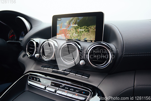 Image of View from inside a car on a part of dashboard with a navigation unit and blurred street in front of a car