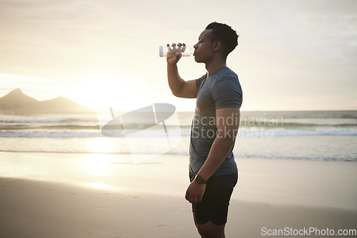 Image of Fitness, beach and black man drinking water at sunset on running break, exercise or mockup. Drink, liquid and African male athlete with bottle for nutrition, hydration or health, wellness and ocean.