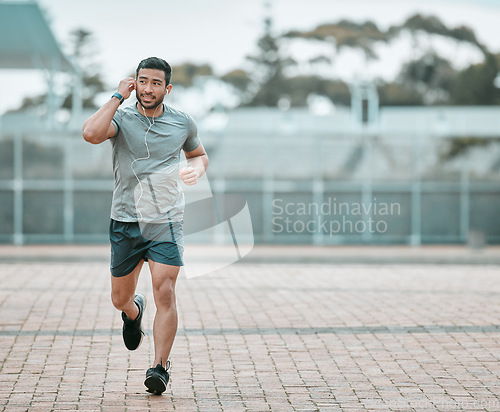 Image of Sports, exercise and man running with earphones for music, radio or podcast for motivation. Fitness, energy and athlete runner doing outdoor cardio workout for race, competition or marathon training.