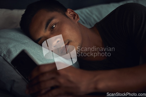 Image of Dark, browse and man in bed with phone surfing internet, social media post or texting with insomnia in home. Wake up, scroll and male in bedroom with cellphone, mobile game and digital app at night.