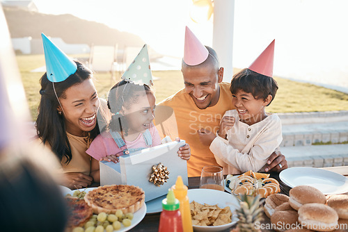 Image of Happy birthday, love and family outdoors for celebration, party and present, laugh and excited. Parents, children and gift for girl child at special event, smile and celebrating with food outside
