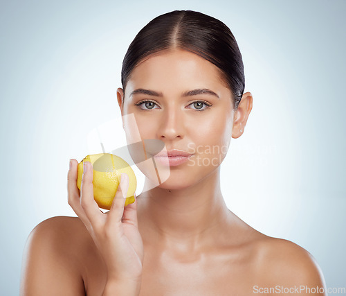 Image of Face, skincare and woman with lemon in studio isolated on a white background. Portrait, natural fruit and serious female model with vitamin c, nutrition and healthy diet, wellness or beauty cosmetics