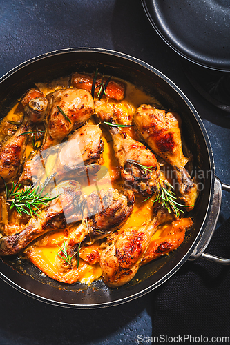 Image of Baked chicken drumsticks with vegetables, casserole dish on black background