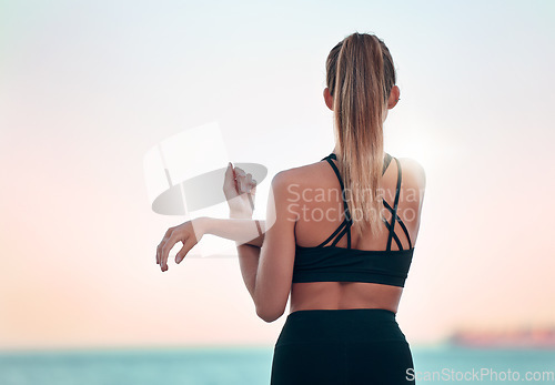 Image of Stretching arm, back and woman at beach for yoga, exercise and ocean mockup space. Fitness, pilates and female athlete stretch for training, workout and health, wellness or warm up at summer sunset.