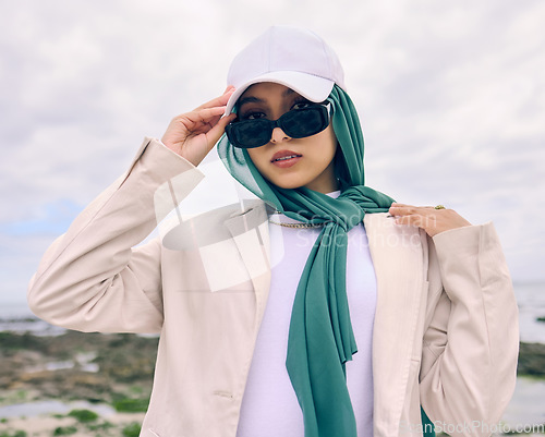 Image of Portrait, fashion or sunglasses with an islamic woman outdoor in a cap and scarf for contemporary style. Muslim, faith or hijab for religion with a trendy young arab person outside in modern clothes