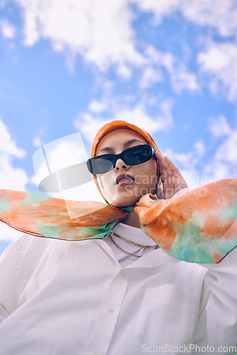 Image of Portrait, fashion or hijab with a saudi woman outdoor on a blue sky background in a scarf and sunglasses for style. Muslim, faith or religion with a trendy young arab person outside in modern clothes