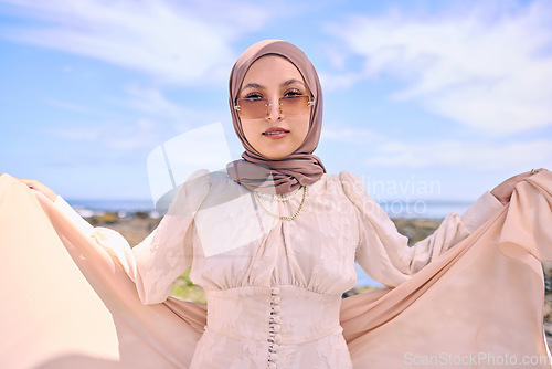 Image of Portrait, fashion or religion with an arab woman outdoor in sunglasses and a scarf for contemporary style. Muslim, faith and dress with a trendy young islamic person posing outside in modern clothes