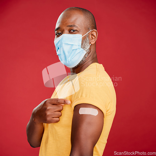 Image of African man, covid and vaccine in studio portrait with pride, healthcare and wellness by red background. Black male model, face mask and point at arm with plaster, medicine and safety to stop virus