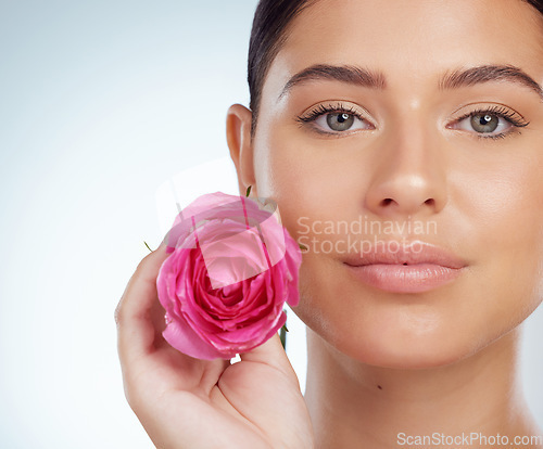 Image of Skincare, face and woman with rose in studio isolated on a white background. Portrait, natural flower and serious female model with pink floral plant for makeup cosmetics, beauty treatment or organic