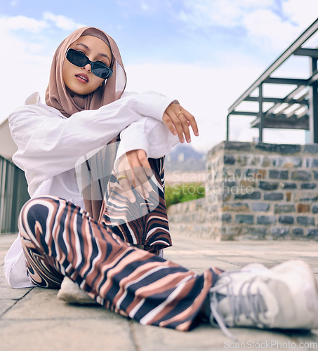 Image of Portrait, fashion or city with a arab woman outdoor in sunglasses and a scarf for urban style. Islam, faith and hijab with a trendy young muslim female person posing outside in contemporary clothes