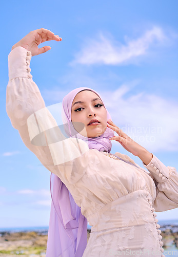 Image of Portrait, fashion or faith with a muslim woman on a blue sky background in a scarf for modern style. Islam, religion and hijab with a trendy young arab person posing outside in contemporary clothes