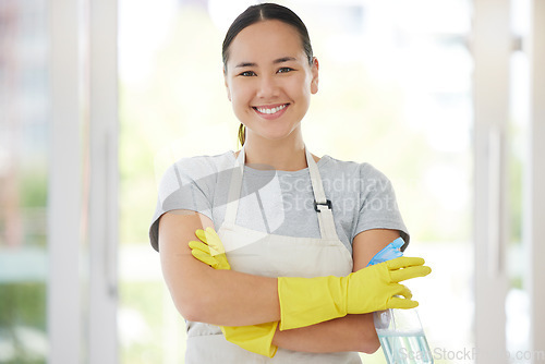 Image of Portrait, cleaning and arms crossed with a woman housekeeper using disinfectant to remove bacteria in a home. Safety, smile and hygiene with a confident young female cleaner working in a living room