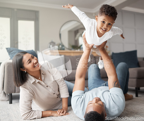 Image of Happy family, kids and flying games in home on living room floor for fun, quality time and relax. Mom, dad and holding boy child in air for play, happiness and support of parents on carpet in lounge