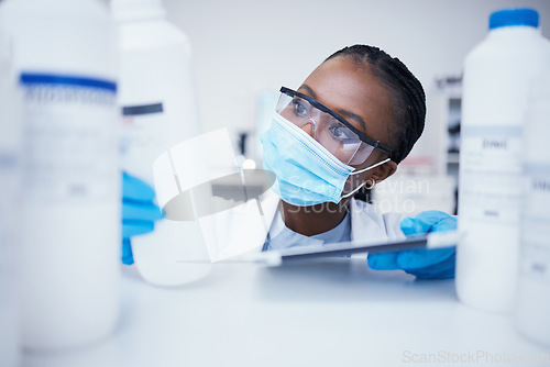 Image of Stock check tablet, chemical bottle and black woman scientist with mask at pharmaceutical lab. Research, label reading and science of a female worker with manufacturing job and chemistry inventory