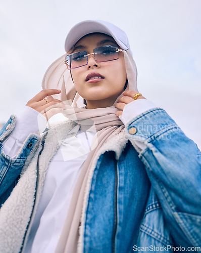 Image of Portrait, fashion or low angle with a muslim woman outdoor in a cap, sunglasses and scarf for contemporary style. Islam, faith or hijab with a trendy young arab person posing alone in modern eyewear