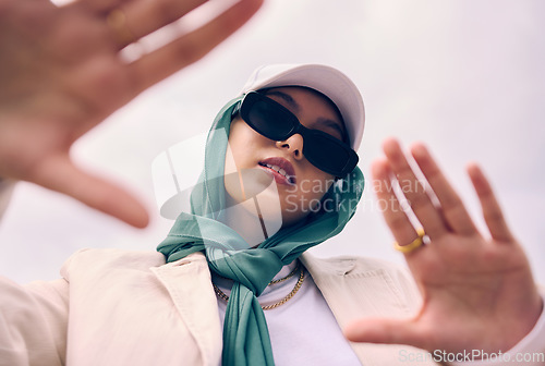 Image of Low angle portrait, woman and city for muslim fashion with gen z aesthetic, streetwear and sky background. Young islamic girl, student and clothes with sunglasses, freedom and outdoor travel in Dubai