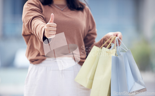 Image of Woman, shopping bag and hand with thumbs up in city for winning, discount or sale outdoors. Closeup of female person or shopper with thumb emoji, yes sign or like for luxury gifts or products in town