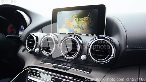 Image of View from inside a car on a part of dashboard with a navigation unit and blurred street in front of a car