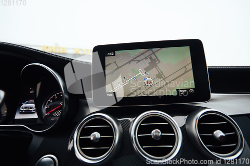 Image of View from inside a car on a part of dashboard with a navigation unit and blurred street in front of a car