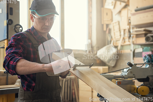 Image of The worker makes measurements of a wooden board