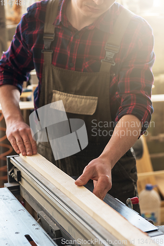 Image of The worker makes measurements of a wooden board