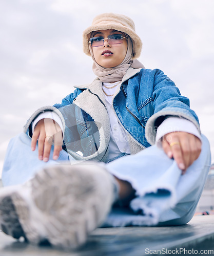 Image of Portrait, fashion or sunglasses with a muslim woman in the city wearing a cap and scarf for contemporary style. Islam, faith and hijab with a trendy young arab person posing outside in modern eyewear