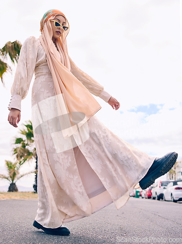 Image of Woman, muslim fashion and street in low angle portrait with gen z aesthetic, beauty and walking in city. Young islamic girl, student and clothes with sunglasses, freedom and travel on road in Dubai