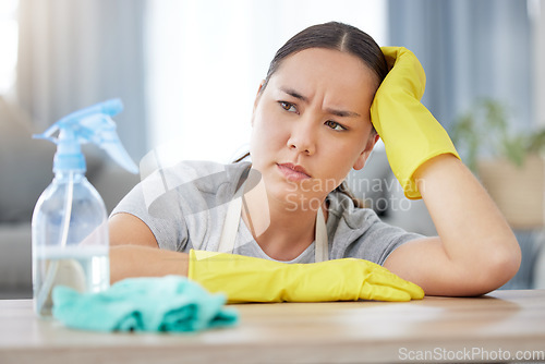 Image of Thinking, annoyed and cleaning with a woman housekeeper using disinfectant to remove bacteria in a home. Idea, frustrated and hygiene with a young female cleaner working in a living room for service