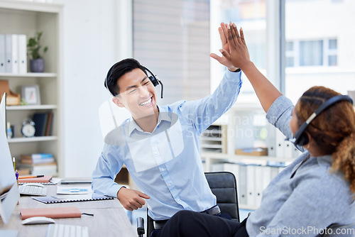 Image of Call center, high five and team celebrate success at desk with headset for telemarketing teamwork. Asian man and a woman agent excited for sales deal, customer service, bonus achievement and target