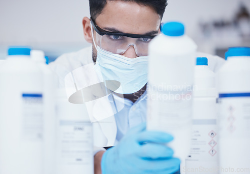 Image of Stock check, chemical bottle and man scientist with mask at pharmaceutical lab working. Research, container label reading and science of a male worker with manufacturing job and chemistry inventory