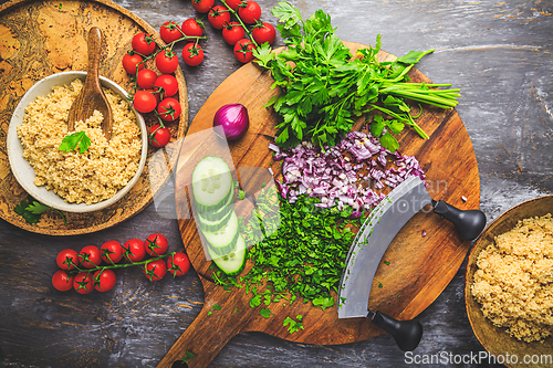 Image of Preparing traditional oriental salad Tabouleh with couscous or bulgur, ingredients on cutting board