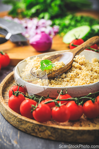 Image of Preparing traditional oriental salad Tabouleh with couscous or bulgur, ingredients on cutting board