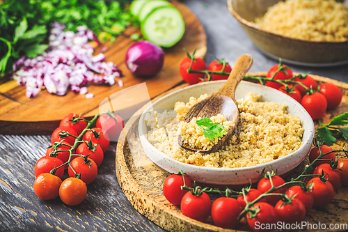 Image of Preparing traditional oriental salad Tabouleh with couscous or bulgur, ingredients on cutting board