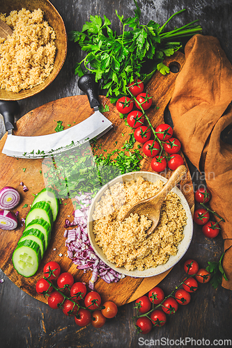 Image of Preparing traditional oriental salad Tabouleh with couscous or bulgur, ingredients on cutting board