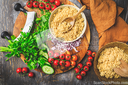 Image of Preparing traditional oriental salad Tabouleh with couscous or bulgur, ingredients on cutting board