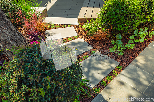 Image of Detail of  garden path with stone slabs with bark mulch and native plants. Landscaping and gardening concept.