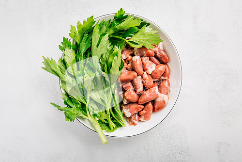 Image of Fresh raw chicken hearts with celery leaves, reading for cooking