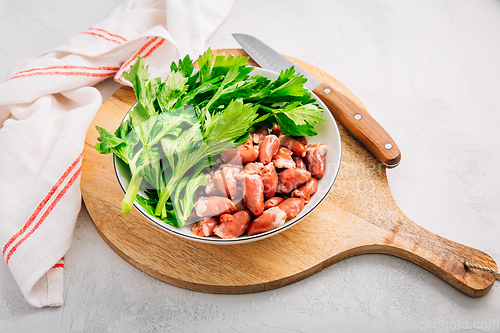 Image of Fresh raw chicken hearts with celery leaves, reading for cooking