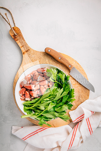 Image of Fresh raw chicken hearts with celery leaves, reading for cooking