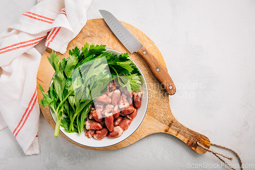 Image of Fresh raw chicken hearts with celery leaves, reading for cooking