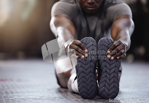 Image of Stretching, feet and exercise with a man at gym for fitness, muscle and training workout. Athlete person with hands on shoes for warm up, goals and performance motivation on floor at a wellness club