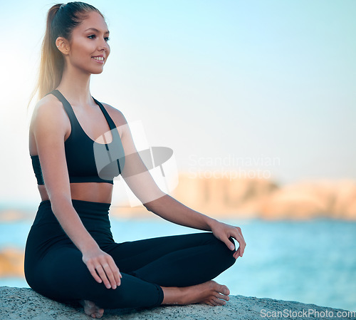 Image of Yoga, zen and wellness on a rock by the sea for mediation, self care with happiness for balance. Meditate, smile and relax with ocean in summer for mental health, spiritual exercise in the outdoor.