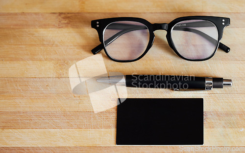 Image of Glasses, pen and notebook on a desk in empty office for abstract background, business and vision. Eye sight, ideas and planner or journal on wooden table for reading and creative writing mockup space