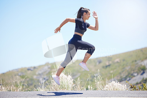 Image of Runner woman, street and jump with speed in nature, fitness and energy for training, wellness and healthy. Girl, fast running and air on road for self care, exercise and workout by hill in summer sun