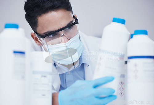 Image of Container check, chemical bottle and man at scientist job with mask at pharmaceutical lab. Research, label reading and science of a male worker with manufacturing work and chemistry inventory