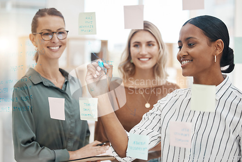 Image of Meeting, planning and a business woman writing on glass with her team for strategy or brainstorming in an office. Collaboration, coaching and leadership with a female employee teaching her colleagues